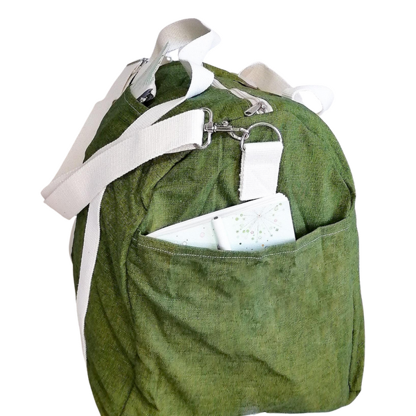 Large Duffel Bag with multiple inner and outer pockets, made with green lightweight denim fabric. Cotton webbing handles and adjustable sling. Side view