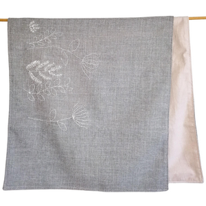 Sage coloured linen table runner with hand embroidered veldt flowers in white.