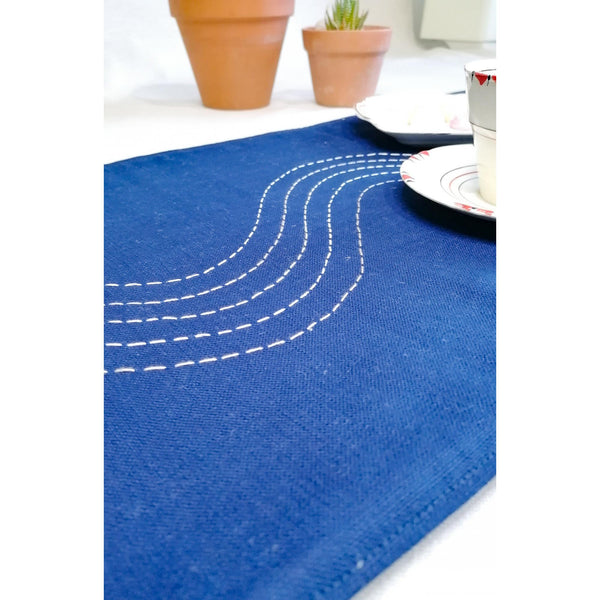 Navy coloured linen table runner with hand embroidered slow waves in shades of white.