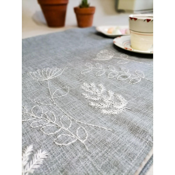 Sage coloured linen table runner with hand embroidered veldt flowers in white.