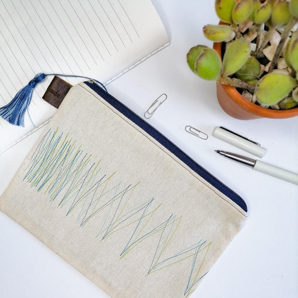 Lined zipper pouch with green & blue stitching lines on front with blue tassle