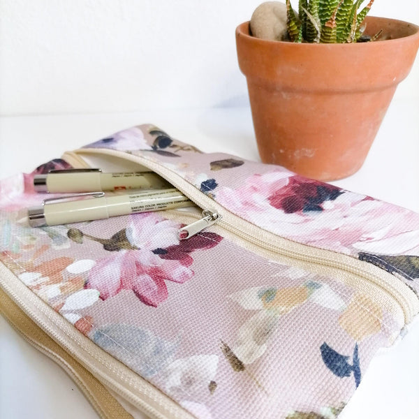 Lined Zipper Cosmetic Bag with extra outer pocket. Muted Pink Floral Fabric with beige zip, Leather tag. Side view of fabric