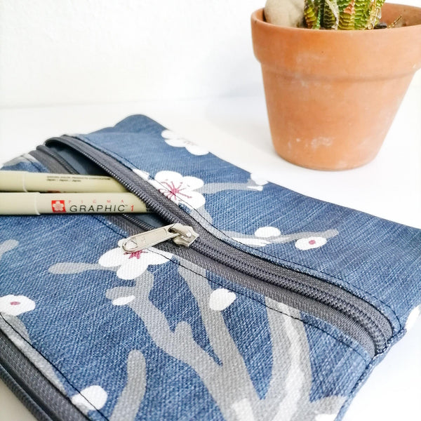 Lined Zipper Cosmetic Bag with extra outer pocket. Grey & white cherry blossom motive on navy background. Grey zip, Leather tag. Side view of fabric