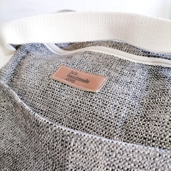 Lined Large Duffel Bag with multiple inner and outer pockets, made with brown tweed fabric. Cotton webbing handles and adjustable sling. Close up view of fabric