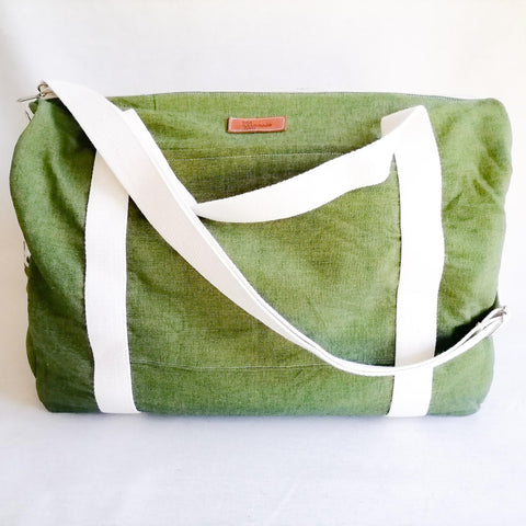 Large Duffel Bag with multiple inner and outer pockets, made with green lightweight denim fabric. Cotton webbing handles and adjustable sling. Front view